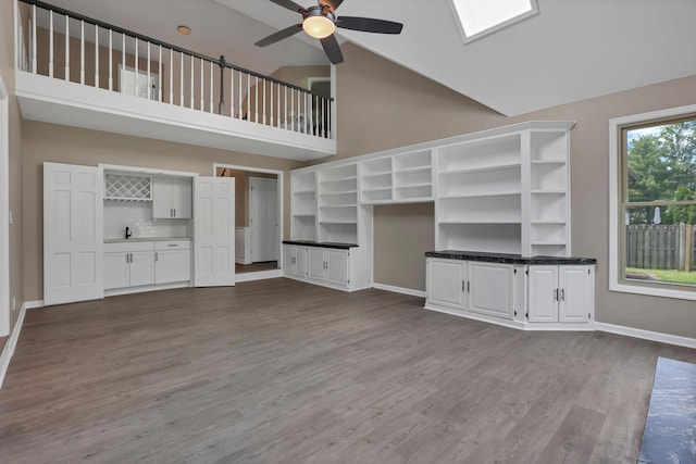 4583 Hunting Creek Dr, Grove City, OH 43123 - unfurnished living room featuring ceiling fan, dark wood-type flooring, high vaulted ceiling, a skylight, and baseboards