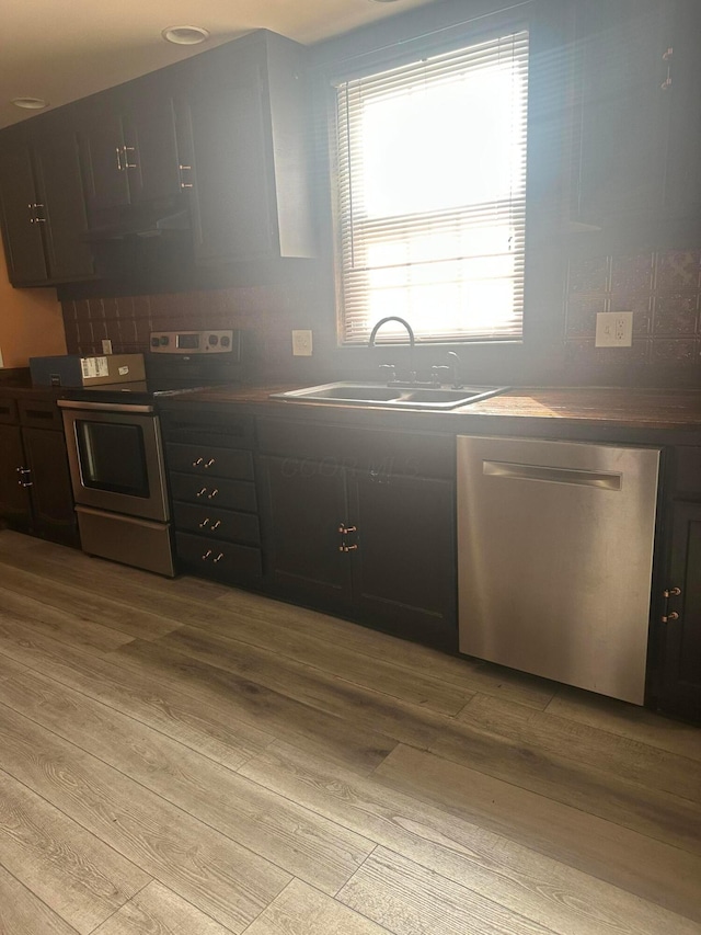 287 W Columbus St, Mount Sterling, OH 43143 - kitchen featuring appliances with stainless steel finishes, a sink, light wood finished floors, dark countertops, and extractor fan
