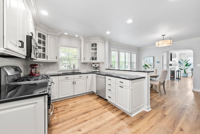 1572 Barrington Rd, Upper Arlington, OH 43221 - kitchen with appliances with stainless steel finishes, a sink, a peninsula, arched walkways, and dark countertops