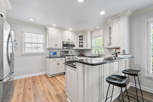 1572 Barrington Rd, Upper Arlington, OH 43221 - kitchen featuring stainless steel appliances, a sink, a kitchen bar, a peninsula, and glass insert cabinets
