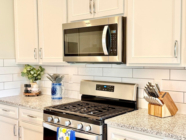 3895 Brody Dr, Grove City, OH 43123 - kitchen with appliances with stainless steel finishes, white cabinets, decorative backsplash, and light stone countertops