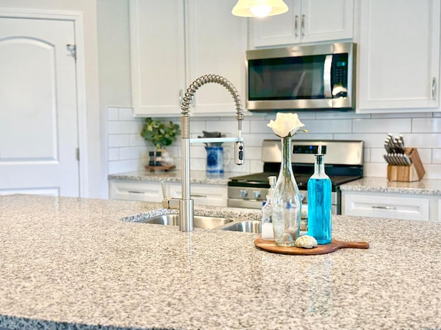 3895 Brody Dr, Grove City, OH 43123 - kitchen with stainless steel microwave, stove, backsplash, and white cabinetry