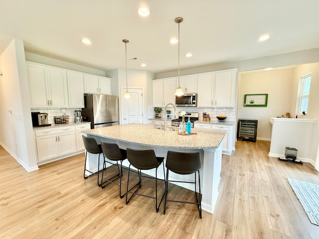3895 Brody Dr, Grove City, OH 43123 - kitchen featuring stainless steel appliances, backsplash, wine cooler, a kitchen island with sink, and white cabinetry