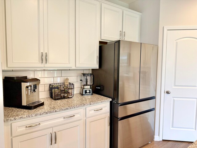 3895 Brody Dr, Grove City, OH 43123 - kitchen featuring freestanding refrigerator, decorative backsplash, white cabinets, light stone countertops, and light wood finished floors