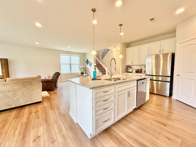 3895 Brody Dr, Grove City, OH 43123 - kitchen with stainless steel appliances, a sink, open floor plan, light wood-type flooring, and white cabinets