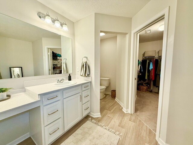 3895 Brody Dr, Grove City, OH 43123 - full bathroom featuring a walk in closet, wood finished floors, vanity, toilet, and a textured ceiling