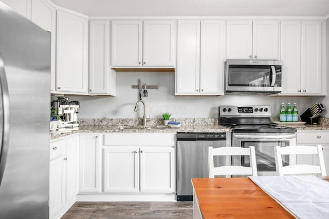 1058 Erickson Ave, Columbus, OH 43227 - kitchen with stainless steel appliances, a sink, wood finished floors, and white cabinets