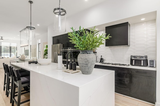 312 Cornelius St, Columbus, OH 43215 - kitchen with stainless steel fridge, gas stovetop, a center island with sink, tasteful backsplash, and recessed lighting