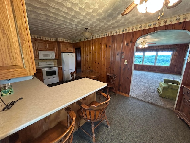 3049 Palace Heights Ln NW, Malta, OH 43758 - kitchen with white appliances, ceiling fan, dark colored carpet, light countertops, and wood walls