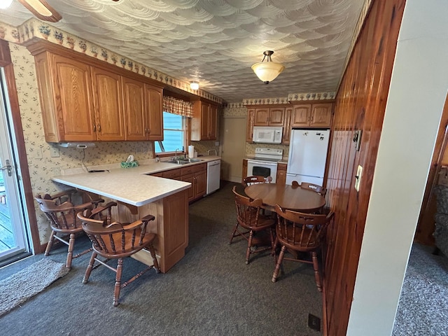 3049 Palace Heights Ln NW, Malta, OH 43758 - kitchen featuring white appliances, a sink, a breakfast bar area, a peninsula, and brown cabinets