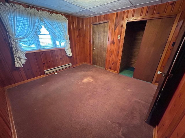 3049 Palace Heights Ln NW, Malta, OH 43758 - unfurnished bedroom featuring a baseboard heating unit, multiple closets, wooden walls, carpet, and baseboards