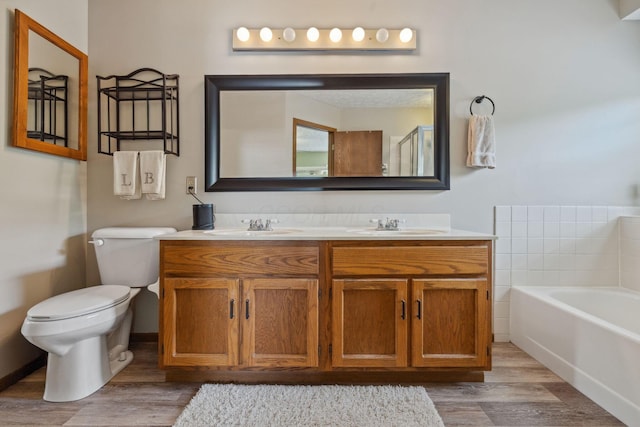 388 Slate Run Dr, Powell, OH 43065 - bathroom with wood finished floors, toilet, double vanity, and a garden tub