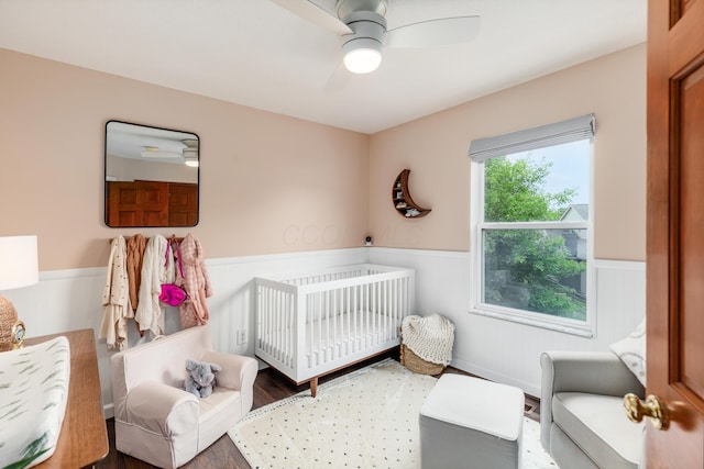 121 Persimmon Ct, Delaware, OH 43015 - bedroom with wainscoting, wood finished floors, a crib, and ceiling fan