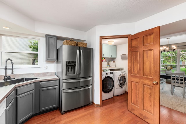 121 Persimmon Ct, Delaware, OH 43015 - kitchen featuring stainless steel refrigerator with ice dispenser, washing machine and clothes dryer, a sink, light wood-style flooring, and a chandelier