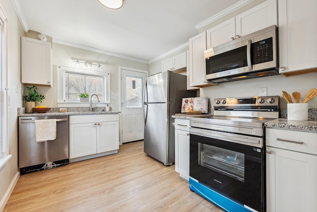 2509 Perdue Ave, Columbus, OH 43211 - kitchen featuring stainless steel appliances, ornamental molding, a sink, light wood-style floors, and white cabinetry