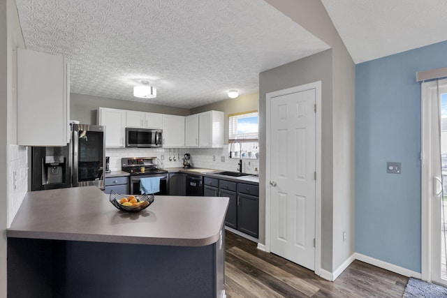 982 Margate Cir, London, OH 43140 - kitchen featuring appliances with stainless steel finishes, a sink, a peninsula, decorative backsplash, and plenty of natural light