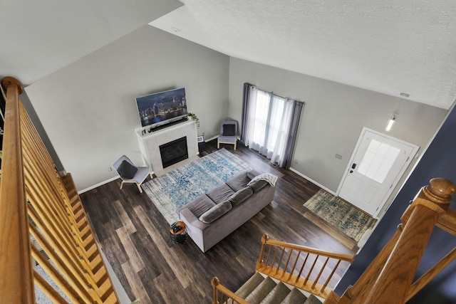 982 Margate Cir, London, OH 43140 - living room featuring vaulted ceiling, baseboards, a fireplace with flush hearth, wood finished floors, and a textured ceiling
