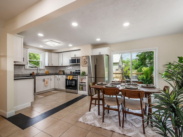1156 S Champion Ave, Columbus, OH 43206 - kitchen featuring stainless steel appliances, decorative backsplash, dark countertops, light tile patterned floors, and recessed lighting