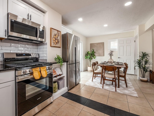 1156 S Champion Ave, Columbus, OH 43206 - kitchen with stainless steel appliances, tasteful backsplash, white cabinets, recessed lighting, and light tile patterned flooring