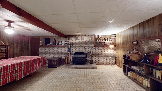 1371 Township Road 200, Bellefontaine, OH 43311 - living area featuring a wood stove, wooden walls, a ceiling fan, and tile patterned floors
