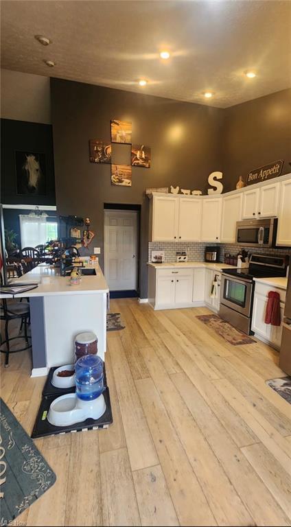 7360 Jones Rd, Nashport, OH 43830 - kitchen with appliances with stainless steel finishes, light wood-style floors, light countertops, and white cabinets