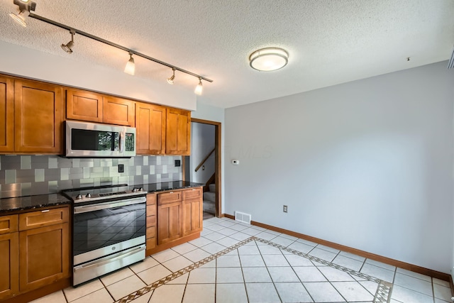 5827 Chanwick Dr, Galloway, OH 43119 - kitchen featuring appliances with stainless steel finishes, brown cabinetry, baseboards, and a textured ceiling