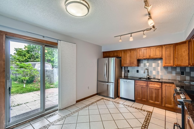 5827 Chanwick Dr, Galloway, OH 43119 - kitchen with stainless steel appliances, a sink, brown cabinetry, tasteful backsplash, and a textured ceiling
