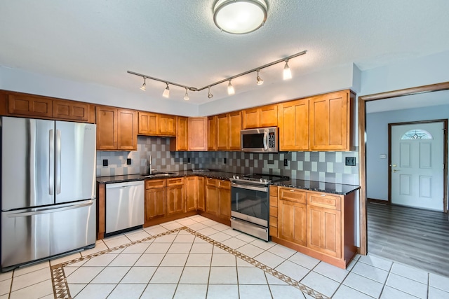 5827 Chanwick Dr, Galloway, OH 43119 - kitchen featuring appliances with stainless steel finishes, backsplash, a sink, light tile patterned flooring, and a textured ceiling