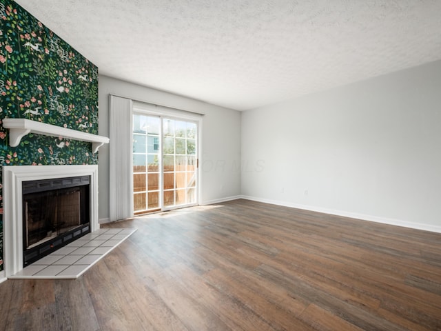 233 Malloy Ln Unit 78A, Blacklick, OH 43004 - unfurnished living room with wood finished floors, a textured ceiling, a tiled fireplace, and baseboards