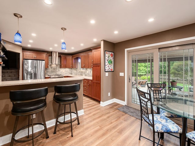 1835 Plains Blvd, Powell, OH 43065 - kitchen featuring appliances with stainless steel finishes, wall chimney exhaust hood, backsplash, light wood-style flooring, and pendant lighting