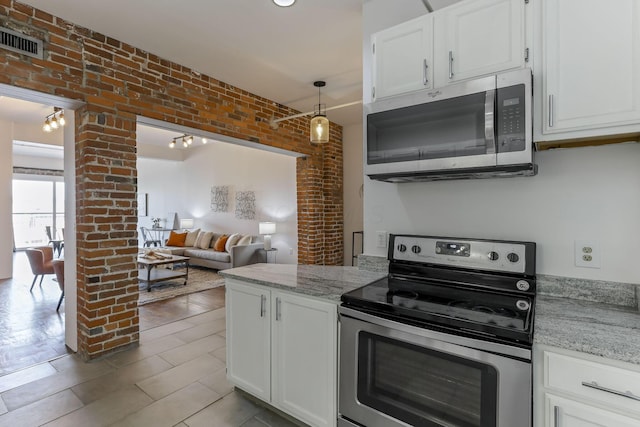432 E Rich St Unit 4A, Columbus, OH 43215 - kitchen featuring appliances with stainless steel finishes, white cabinetry, brick wall, light stone counters, and decorative light fixtures