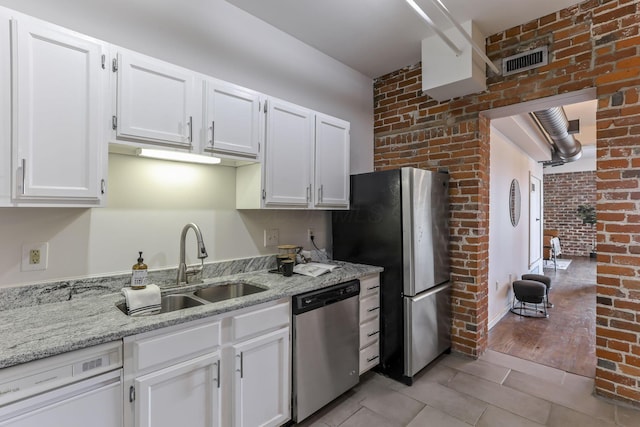 432 E Rich St Unit 4A, Columbus, OH 43215 - kitchen with appliances with stainless steel finishes, white cabinets, light stone countertops, brick wall, and light tile patterned floors