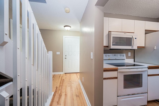 1845 Messner Dr Unit 57E, Hilliard, OH 43026 - kitchen featuring white appliances, white cabinetry, light wood-style flooring, a textured ceiling, and light countertops
