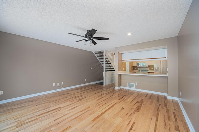 1845 Messner Dr Unit 57E, Hilliard, OH 43026 - unfurnished living room with light wood finished floors, a ceiling fan, a textured ceiling, stairway, and recessed lighting