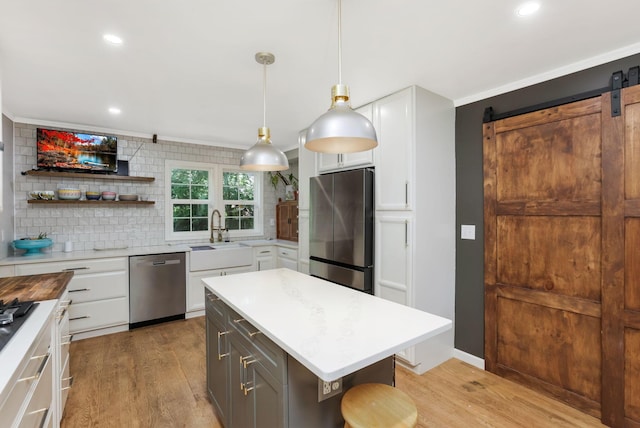 4286 Evansdale Rd, Columbus, OH 43214 - kitchen featuring appliances with stainless steel finishes, light wood-style flooring, white cabinetry, tasteful backsplash, and a barn door