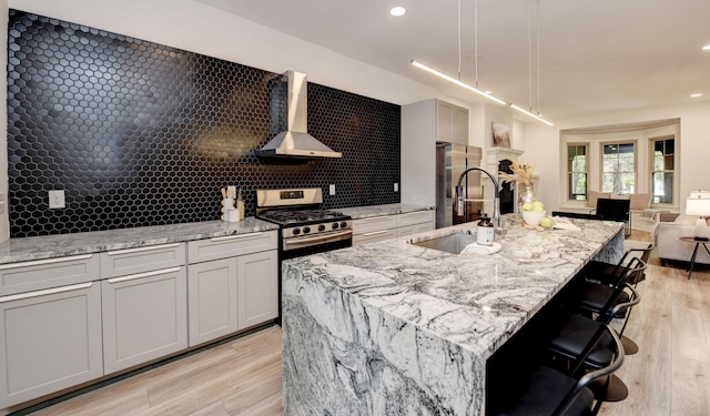 39 Auburn Ave, Columbus, OH 43205 - kitchen with wall chimney range hood, a sink, light stone countertops, appliances with stainless steel finishes, and a kitchen island with sink