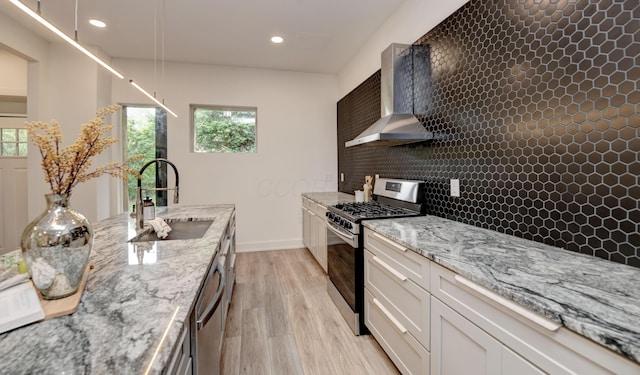 39 Auburn Ave, Columbus, OH 43205 - kitchen with wall chimney range hood, stainless steel appliances, a sink, light wood-style floors, and plenty of natural light