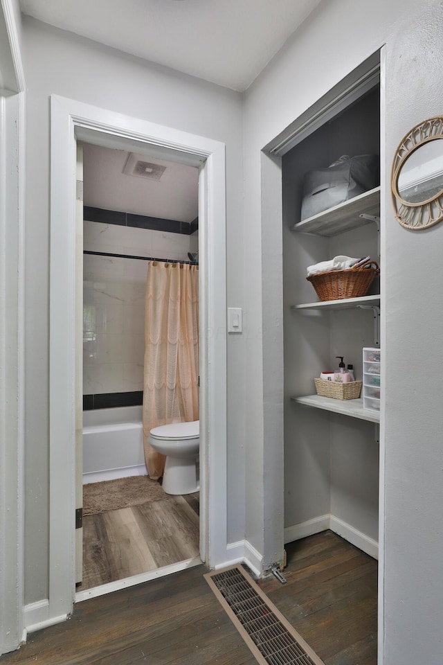 3216 Howey Rd, Columbus, OH 43224 - full bathroom with wood finished floors, toilet, shower / bath combo with shower curtain, and baseboards