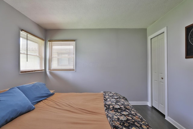 3216 Howey Rd, Columbus, OH 43224 - bedroom featuring dark wood-style flooring, a textured ceiling, baseboards, and a closet