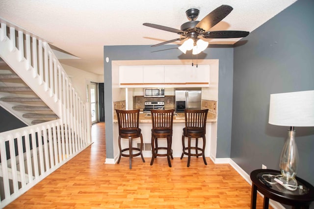 2043 Coleman Dr Unit 6F, Columbus, OH 43235 - kitchen with appliances with stainless steel finishes, light wood-style flooring, decorative backsplash, ceiling fan, and white cabinets