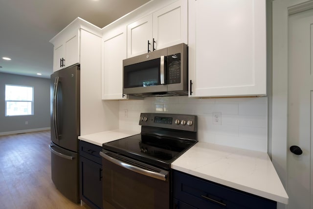 1275 Wager St, Columbus, OH 43206 - kitchen with appliances with stainless steel finishes, backsplash, white cabinets, light wood finished floors, and recessed lighting