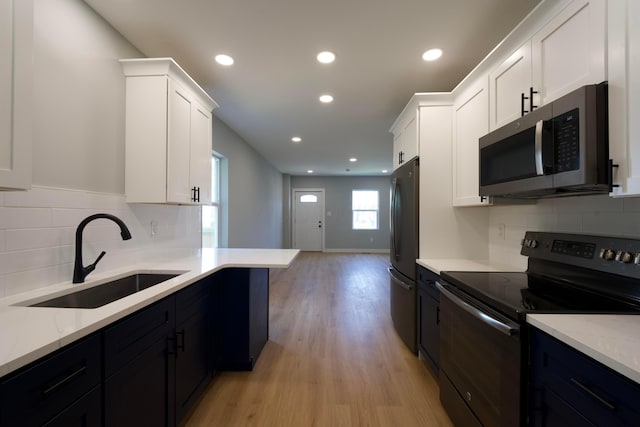 1275 Wager St, Columbus, OH 43206 - kitchen featuring appliances with stainless steel finishes, light wood-style flooring, white cabinetry, recessed lighting, and light stone counters