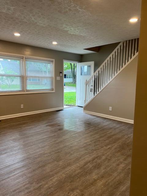 1416 Benson Dr, Columbus, OH 43227 - unfurnished living room with stairs, a textured ceiling, dark wood-style floors, and recessed lighting