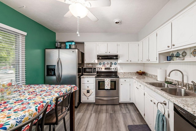 6563 Karl Rd, Columbus, OH 43229 - kitchen with stainless steel appliances, under cabinet range hood, light countertops, white cabinetry, and a textured ceiling