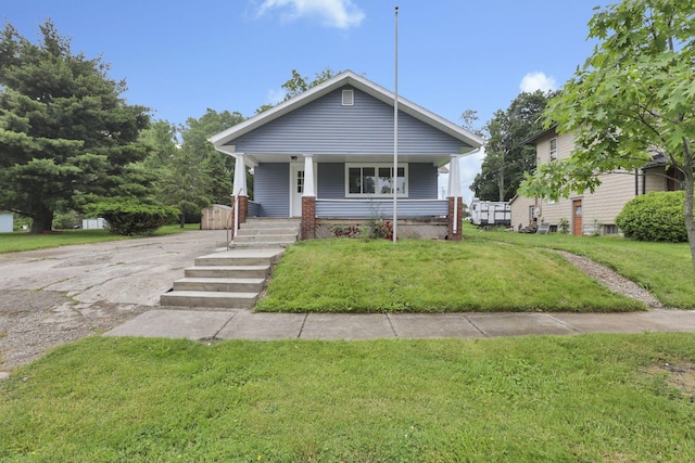 704 N Detroit St, Bellefontaine, OH 43311 - bungalow-style house with covered porch, a front yard, and asphalt driveway