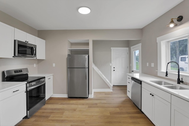 704 N Detroit St, Bellefontaine, OH 43311 - kitchen with appliances with stainless steel finishes, a sink, light wood finished floors, and plenty of natural light