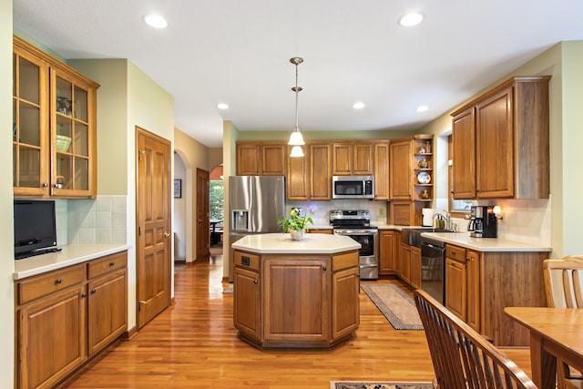 5839 Ketch St, Lewis Center, OH 43035 - kitchen with stainless steel appliances, arched walkways, light wood-style flooring, brown cabinets, and backsplash