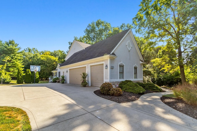 5839 Ketch St, Lewis Center, OH 43035 - view of side of property featuring an attached garage, concrete driveway, stucco siding, stone siding, and a shingled roof
