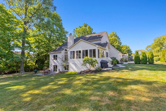 5839 Ketch St, Lewis Center, OH 43035 - rear view of house with a chimney, a lawn, a patio, and a sunroom