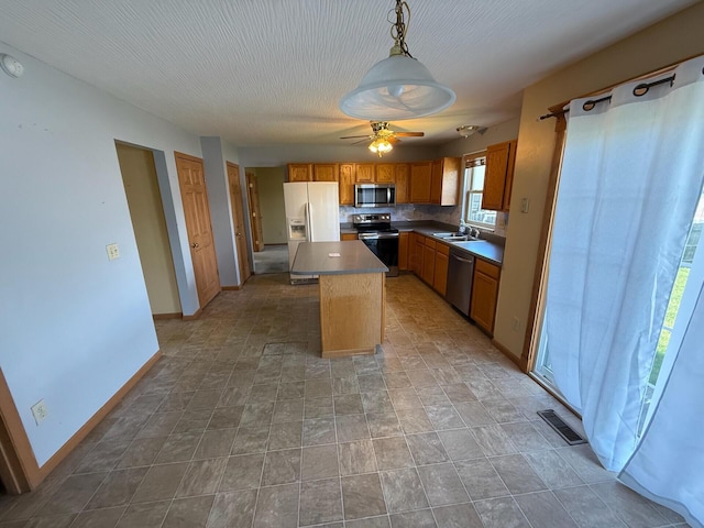 3126 Zach Ct, Columbus, OH 43219 - kitchen featuring appliances with stainless steel finishes, a sink, baseboards, a kitchen island, and ceiling fan